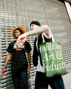 Models wear Provide's black T-shirt and green Art & Industry tote bag.