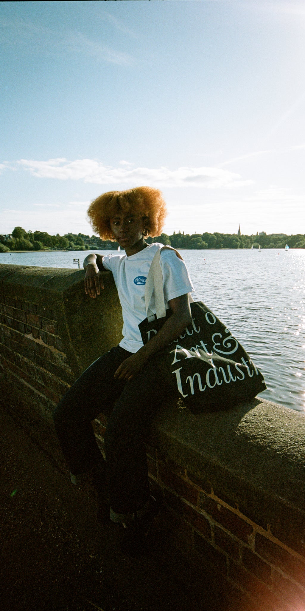 Model wears Provide's white and blue T-shirt and black Art & Industry tote bag.