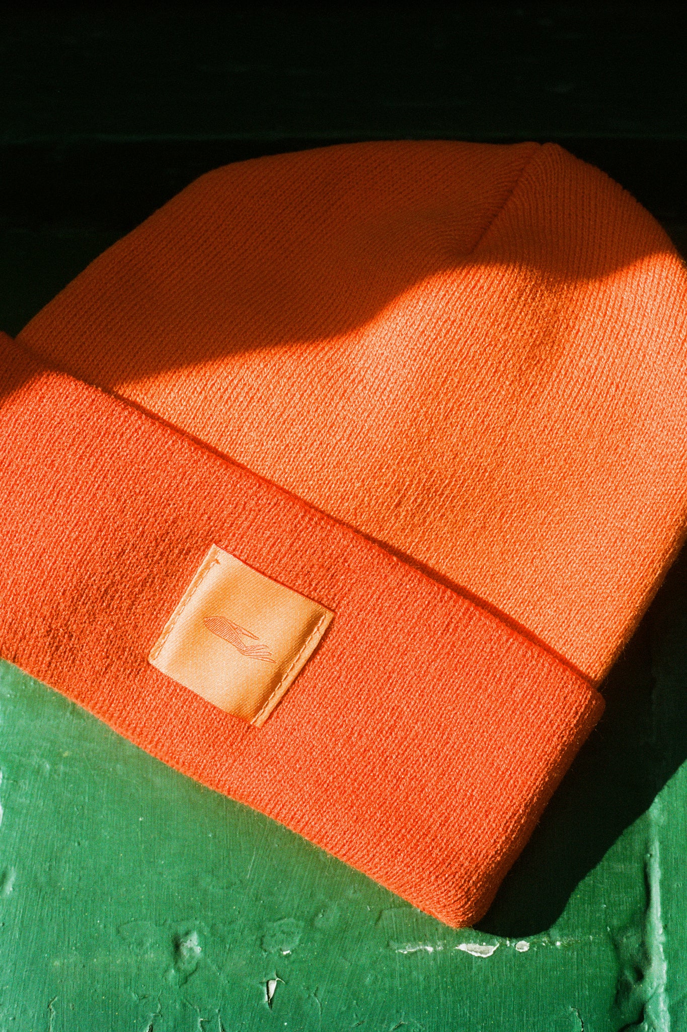 Provide orange beanie with hand logo patch stitched on to front (front)