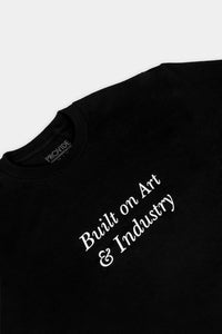 Provide black Tee with large Built on Art and Industry chest print (close up)
